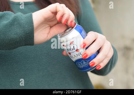 KHARKOV, UCRAINA - 16 OTTOBRE 2020: Giovane ragazza detiene 1664 lattine di birra Kronenbourg Blanc all'aperto. 1664 Blanc è la birra di grano della birreria francese K. Foto Stock