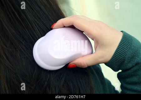 KHARKOV, UCRAINA - OTTOBRE 16 2020: La giovane ragazza tiene il groviglio Teezer capelli rosa. Tangle Teezer è un produttore britannico di spazzole per capelli detangenti Foto Stock