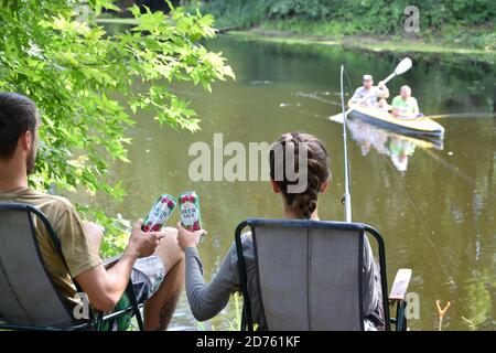 KHARKOV, UCRAINA - 22 2020 AGOSTO: Giovani ragazzi e ragazze si acclamano con bewermix barattoli di stagno all'aperto durante la pesca. Beermix è prodotto da Obolon manu Foto Stock