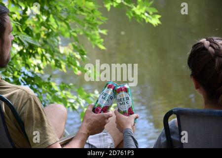 KHARKOV, UCRAINA - 22 2020 AGOSTO: Giovani ragazzi e ragazze si acclamano con bewermix barattoli di stagno all'aperto durante la pesca. Beermix è prodotto da Obolon manu Foto Stock