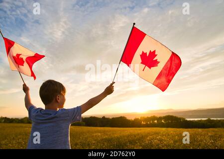 Adorabile ragazzo caucasico felice carino che tiene bandiera canadese sul spalla del padre Foto Stock