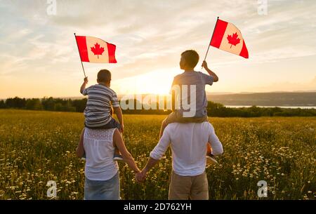 Adorabili cute felici caucasici ragazzi tenendo bandiera canadese sul spalla del padre Foto Stock