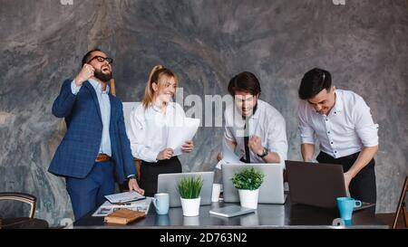 Euforic team di affari eccitati celebrare la vittoria aziendale insieme in ufficio, felice gruppo di professionisti overjoyed gioire la vittoria dell'azienda, lavoro di squadra Foto Stock