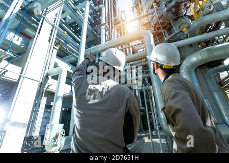 Ingegnere industriale o lavoratore che controlla la conduttura presso l'impianto di raffineria di petrolio e gas forma zona industriale con alba e cielo nuvoloso, petrolio e gas industria con Foto Stock