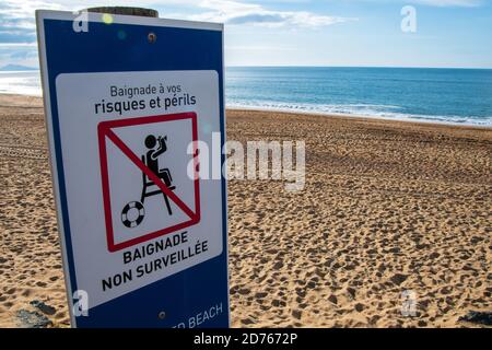 Cartello di avvertimento scritto in francese che indica 'spiaggia non sorvegliata' sulla costa atlantica. "Fare il bagno a proprio rischio" scritto in francese in alto Foto Stock