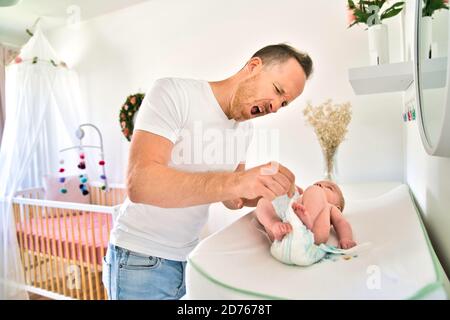 Un padre che cambia il pannolino del bambino nella stanza dei bambini Foto Stock