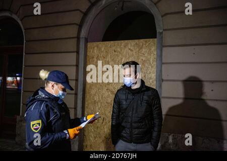 Lubiana, Slovenia. 20 Ott 2020. Un poliziotto è visto controllare un certificato di manís dal suo datore di lavoro, che gli permette di essere fuori durante il coprifuoco notturno. Dopo la ri-proclamazione di un'epidemia, la Slovenia ha imposto un coprifuoco notturno a livello nazionale per combattere il suo aumento di infezioni da coronavirus. itís la prima volta in Slovenia è stato dichiarato un coprifuoco dall’inizio dell’epidemia. Il coprifuoco è in vigore dalle 21:00 alle 6:00. Credit: SOPA Images Limited/Alamy Live News Foto Stock