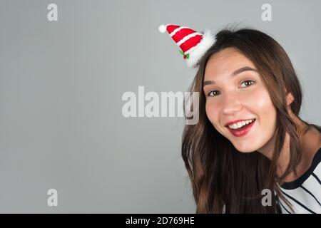 Una giovane donna felice con decorazione di Natale nei suoi capelli guarda nella macchina fotografica. Festeggiamo Natale e Capodanno. Foto di alta qualità Foto Stock