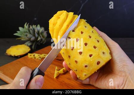 Coltello per la pelatura e la rimozione del disco rigido e. occhi di un ananas fresco maturo Foto Stock