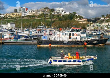 Una piccola barca entra nel porto turistico della pittoresca cittadina di Torquay, nel Devon meridionale. Foto Stock