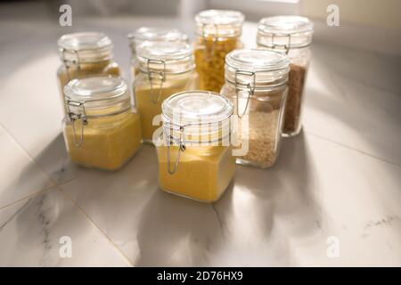 Raccolta di vasi di deposito di prodotti di grano sopra su cucina. Vasetto di cereali nell'armadio della cucina Foto Stock