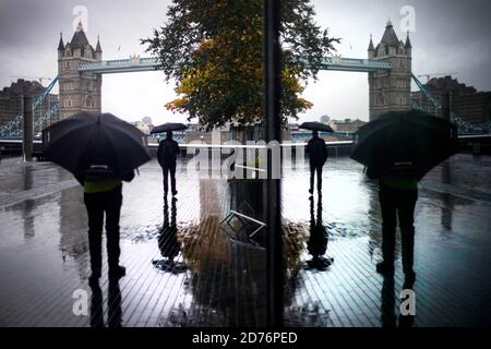 I pendolari del mattino camminano vicino al Tower Bridge nel centro di Londra, mentre gli avvertimenti meteorologici vengono emessi davanti a Storm Barbara, che si prevede porterà venti di forza di gale e forti docce nelle parti meridionali del Regno Unito. Foto Stock