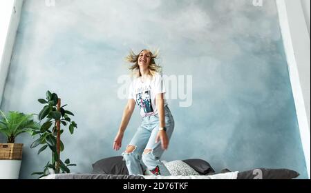 Ragazza bionda felice che si diverte nella camera da letto sul letto. Foto Stock