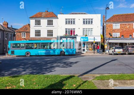 Un autobus blu parcheggiato all'esterno di un negozio di beneficenza sue Ryder con un cartello blu corrispondente, su Tenterden High Street, Kent, UK Foto Stock