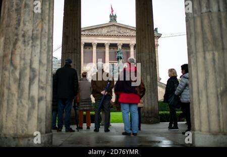 Berlino, Germania. 21 Ott 2020. I turisti si trovano sull'Isola dei Musei tra le colonne di fronte all'Alte Nationalgalerie. Sull'Isola dei Musei di Berlino decine di opere d'arte sono state apparentemente deliberatamente danneggiate. Secondo i media, il danno si è già verificato il 3 ottobre. I danni riguardano circa 70 oggetti nel Museo Pergamon, il Museo Neues, l'Alte Nationalgalerie e altri luoghi. Erano stati spruzzati con un liquido oleoso. Credit: Bernd von Jutrczenka/dpa/Alamy Live News Foto Stock