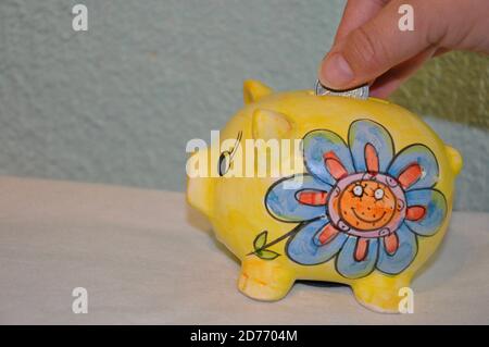 Piggy Bank, Money bag e monete su tavola bianca. Risparmio di denaro. Borsa piena di soldi e giallo Piggy Bank su sfondo blu. Foto Stock