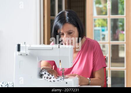 Donna che fa le maschere fatte a casa su macchina da cucire, Foto Stock
