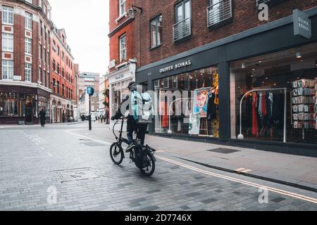 LONDRA, UK-21 MARZO 2019. Un'azienda di consegna dei ciclista Deliveroo che accelera attraverso le strade della città con una consegna di cibo caldo da asperi e ristoranti Foto Stock