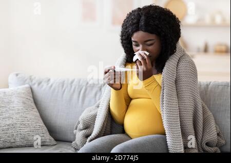 Giovane donna africana incinta che si sente malata con febbre alta Foto Stock