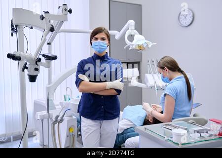 Ritratto di giovane dottore dentista in maschera medica viso in studio dentistico Foto Stock