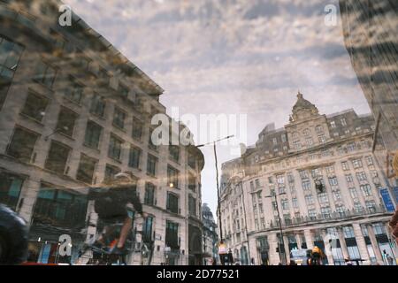 Riflessione degli edifici nel quartiere finanziario di Londra (King William Street, vicino alla stazione della metropolitana Monument) in un pozze. Foto Stock
