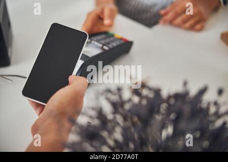 Cliente che paga un acquisto con l'aiuto di un telefono Foto Stock