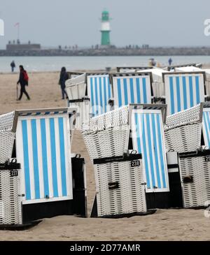 21 ottobre 2020, Meclemburgo-Pomerania occidentale, Warnemünde: Sulla spiaggia del Mar Baltico, gli escursionisti sono fuori sotto la pioggia, le sedie a sdraio sono pronte per il trasporto. Foto: Bernd Wüstneck/dpa-Zentralbild/dpa Foto Stock