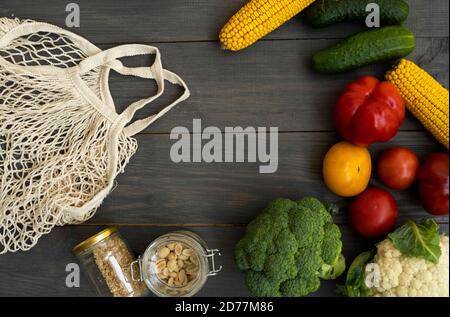 Mazzetto di verdure miste biologiche e sacchetto riutilizzabile in rete di cotone su un tavolo. Concetto di zero sprechi. Stile di vita ecocompatibile. Generi alimentari e borse ecologiche Foto Stock