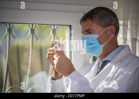 Medico di sesso maschile sicuro in ospedale con una siringa e indossare una maschera medica. Foto Stock