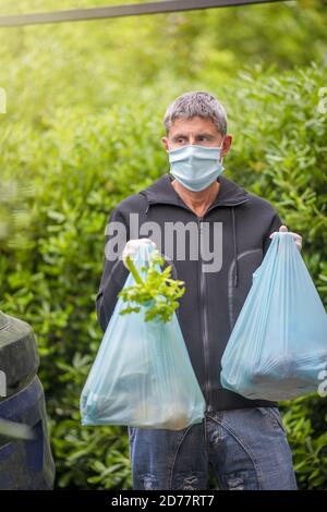 Maschio che porta generi alimentari a casa in covid pandemic . Foto Stock