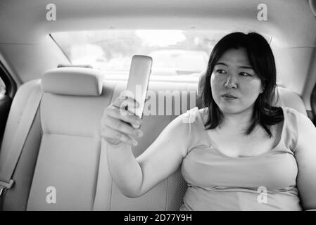 Bella donna asiatica in sovrappeso all'interno della macchina intorno alla città Foto Stock