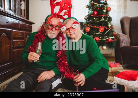 Coppia anziana a casa che ha una celebrazione di Natale su un videochiamata Foto Stock