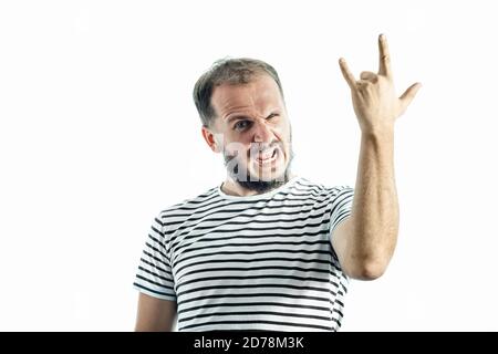Uomo bearded che indossa t-shirt a righe che mostra la mano di rock e roll, corna diavali segno mano gesto isolato su bianco Foto Stock