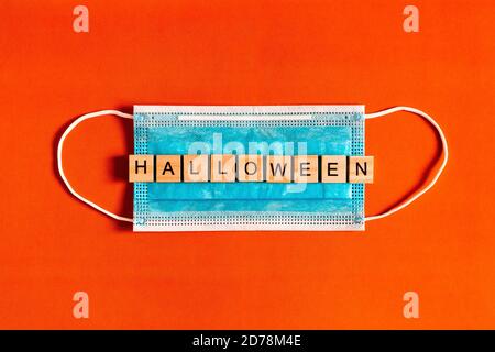 Scritta Halloween su una maschera medica protettiva su sfondo nero con silhouette di pipistrelli in carta nera, Halloween 2020 in una nuova realtà Foto Stock
