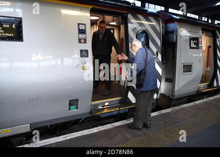 L'uomo aiuta i gentiluomini anziani a salire a bordo del treno Virgin a Euston London. Foto Stock