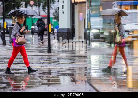 Londra, Regno Unito. 21 Ott 2020. Gli ombrelli sono in su che smorzano gli spiriti in Oxford Street. Tempi difficili per i rivenditori come il come la pioggia cade e le restrizioni di Coronavirus cominciano ad aumentare di nuovo. Credit: Guy Bell/Alamy Live News Foto Stock