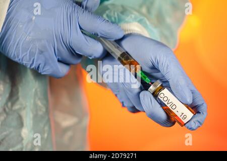 Un medico con guanti blu aspira una fiala in una siringa. Vaccino medico contro il concetto di influenza coronavirus flacone di iniezione per vetro medico Foto Stock