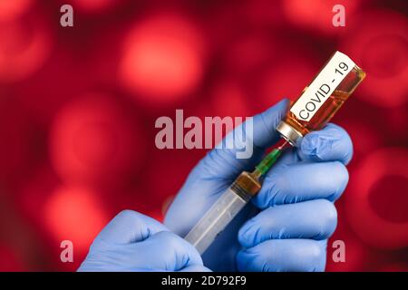 Un medico con guanti blu aspira una fiala in una siringa. Vaccino medico contro il concetto di influenza coronavirus flacone di iniezione per vetro medico Foto Stock