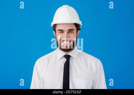 Giovane ingegnere civile sopportato su sfondo blu isolato. Studio ritratto dell'architetto primo piano Foto Stock