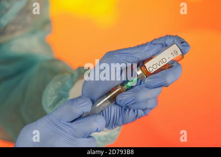 Un medico con guanti blu aspira una fiala in una siringa. Vaccino medico contro il concetto di influenza coronavirus flacone di iniezione per vetro medico Foto Stock