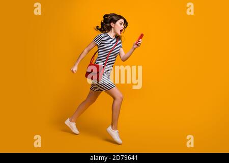 Sono in ritardo Full corpo foto profilo di pazza corsa signora telefono tempo di controllo di lavoro fretta bocca aperta indossare casual scarpe con pochette a righe mini dress Foto Stock