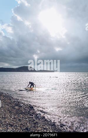 Vladivostok, Russia - 04 ottobre 2020: Winsurfer alla luce del sole che si prepara per la vela in tempesta e ventosa giorno Foto Stock