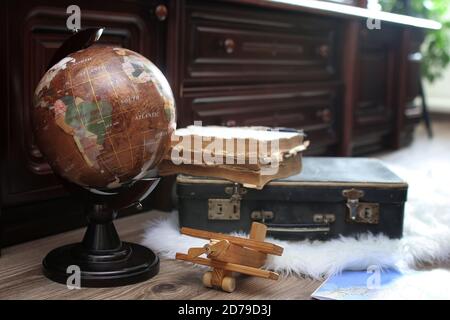 composizione su un globo d'epoca con pavimento in legno e vecchia pelle valigia Foto Stock