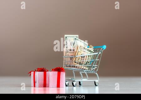 Concetto di pianificazione delle spese di Natale, scatole regalo e carrello pieno di soldi Foto Stock