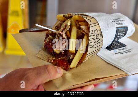 Piatto di tenuta a mano con un tradizionale kebab di giros cipriota con carne, insalata e patatine in pitta pane Foto Stock