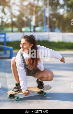 La giovane donna sta cavalcando un longboard nel parco Foto Stock