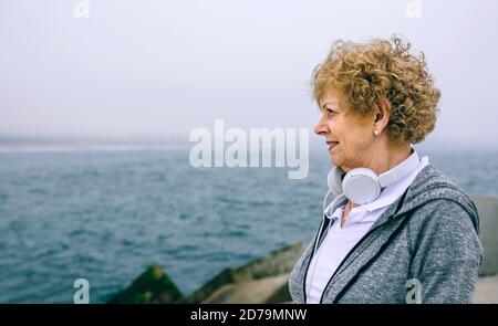 Donna sportiva anziana che guarda il mare Foto Stock