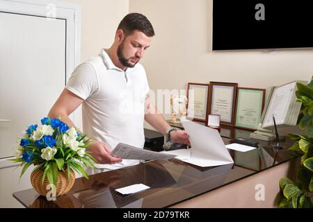 Uomo alla reception dell'ufficio che lavora con i documenti Foto Stock