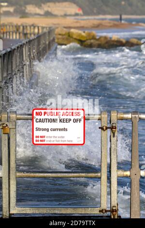 WarningSign su Mudeford Quay Christchurch UK avvertimento di forti correnti e nessun accesso pubblico con ondulato, mare pesante in background Foto Stock