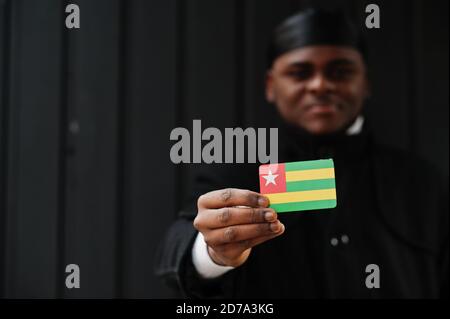 Uomo africano indossare durag nero tenere Togo bandiera a mano isolato sfondo scuro. Foto Stock